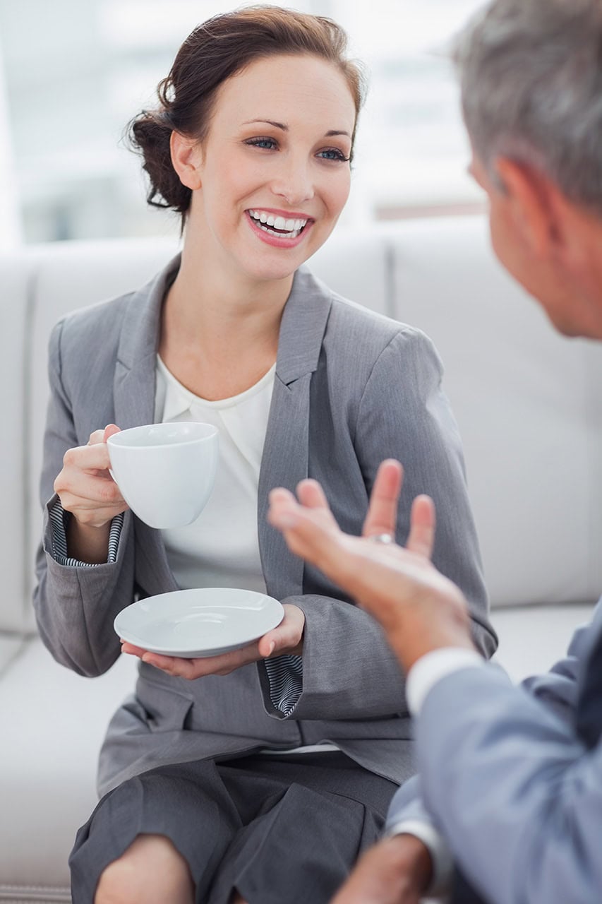 Kommunikation im Beruf, professioneller Austausch, Geschäftsmeeting, Frau mit Tasse im Gespräch, Business-Umfeld, freundliche Unterhaltung, Geschäftliche Kommunikation, Networking, Büro, professionelles Teamwork.